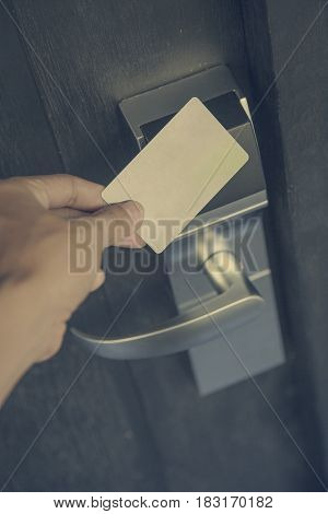 Hand holding keycard hotel front electronic sensor of room door