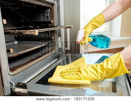 Man With Bottle Of Spray And Rag Cleaning Oven