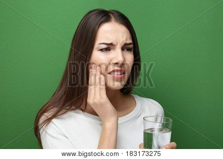 Beautiful young woman with medicine  suffering from toothache on color background