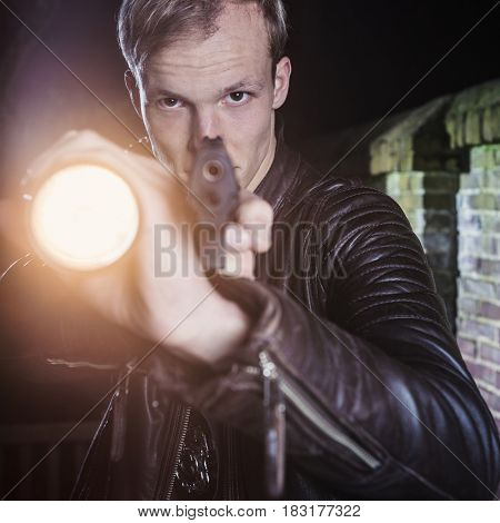 Special Agent in twilight, dusk pointing his gun and torch on suspect in an alley