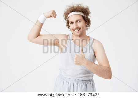 Portrait of retro guy in grey vest tucked into sport pants on grey background
