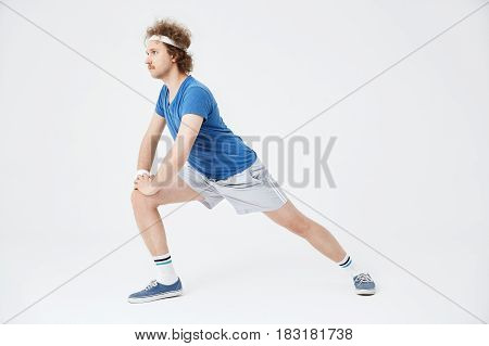 Man in blue shirt, grey shorts, long socks and blue sneakers, lunging forward, looking straight