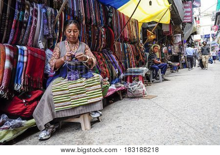 Dharamsala India september 8 2010: Old indian woman knitting in front of her shop on a local street market Dharamsala India.