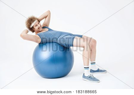 Tired retro man curling up on exercise ball. Looking exhausted, isolated on white background