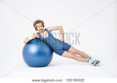 Man working on obliques, lying on his side, training with big purple exercise ball