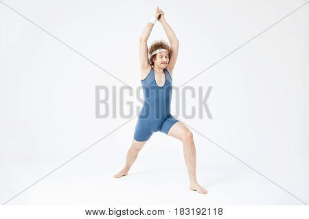 Practicing yoga. Retro man doing virabhadrasana with eyes closed, enjoying moment. Peace and harmony concept.