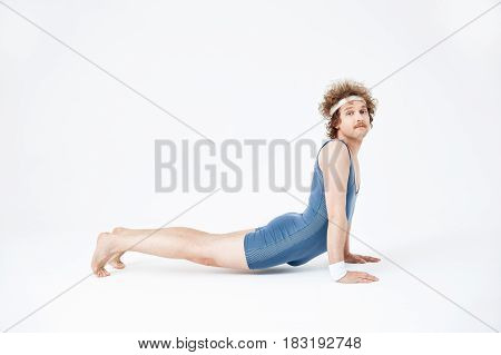 Bhujanqasana. Man in blue jumpsuit practising yoga for first time, doing his best, looking proud