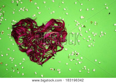 Composition of petals in red on a green background