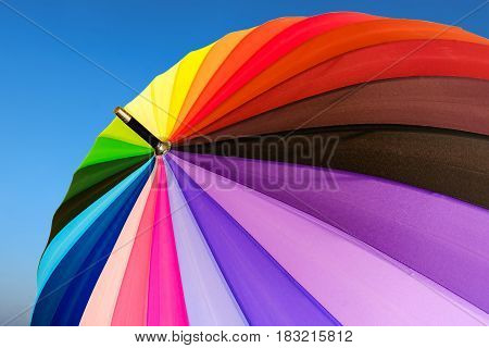 Colorful umbrella top view on blue sky background.