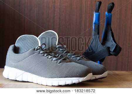 Gray sport shoes with Nordic Walking sticks and orthopedic insoles. Pair of sneakers on wooden background