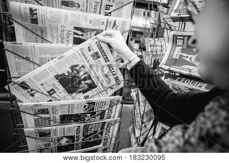 PARIS FRANCE - APRIL 24: Woman buy looks at press kiosk at Italian Corriere della Sera newspaper with pictures of French Presidential election candidates Emmanuel Macron Marine Le Pen a day after first round of French Presidential election on April 23 201