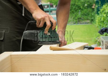 Man sanding wooden board DIY project in garden