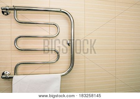Towel hangs on modern brand new chrome dryer in bathroom