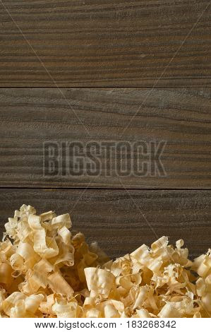 Light brown wood shavings from carpenter's hand planer or chisel work on wooden boards background with copy space