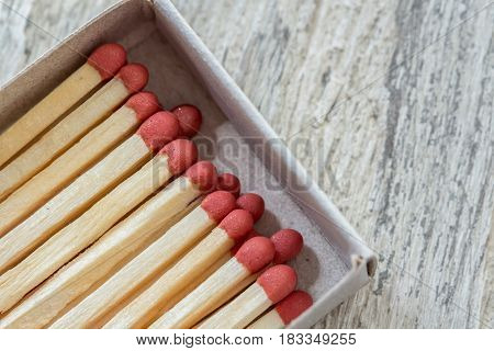 Matches in opened matchbox on wooden surface, close-up