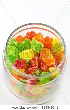 Sweet colorfful turkish delight in the opened glass jar isolated on white background, close-up