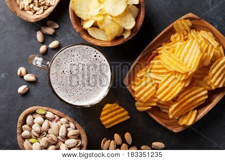 Lager beer and snacks on stone table. Nuts, chips. Top view
