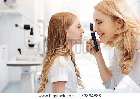What a nice eyes you have. Careful scrupulous distinguished ophthalmologist examining patients eye ground while holding a regular consultation and running a routine checkup