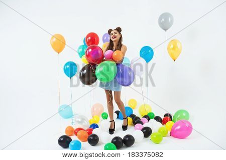 Happy woman in cool summer wear looks glad playing with helium ballons after bright party