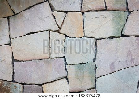 Multi-colored and multi-sized pale rocks wall grunge texture background.