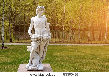Sculpture in classic style. Statue of a man hunter with bow and dog.