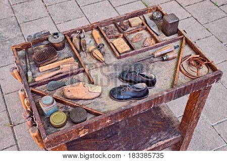 work table with small shoes for children and old tools of the artisan shoemaker for repair and finishing shoe