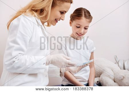 Necessary vitamins. Very attentive girl patient keeping hands together bowing her head while looking at organizer for pills