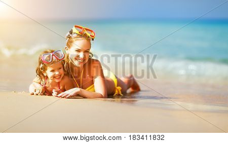 Happy family mother and chid daughter in masks for swimming on the beach in summer