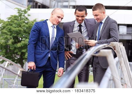 Three Businessmen Discussing Document Outside them Office