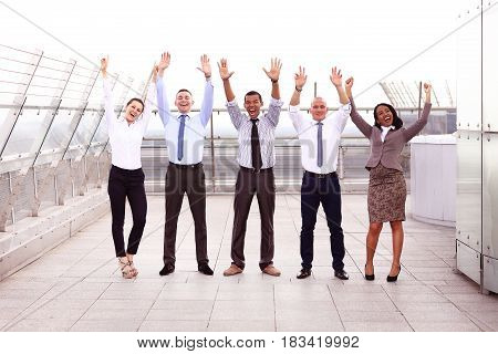Business winners. Full length of group of happy young people in formal wear celebrating, gesturing, keeping arms raised and expressing positivity.