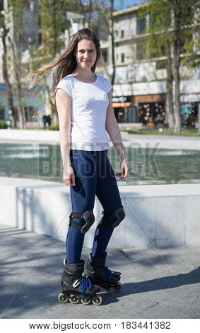 Beautiful and happy Roller Girl skating in the park. She is smiling