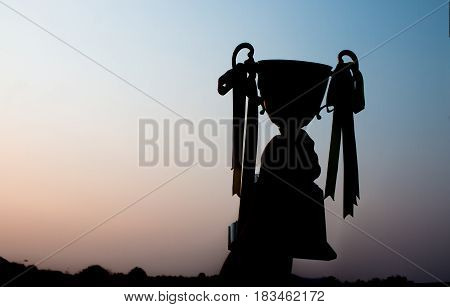 winner and champion concept Silhouette of Hand holding championship trophy against blue sky