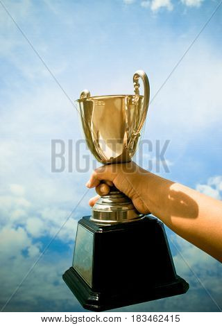 winner and champion concept Hand holding championship trophy against blue sky