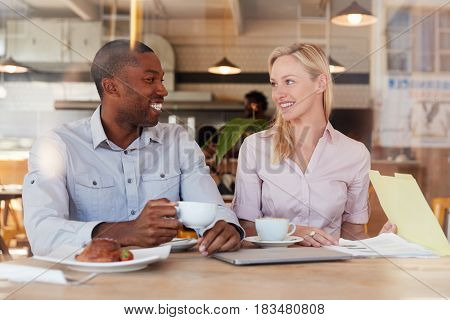 Two Businesspeople Meet In Coffee Shop Shot Through Window