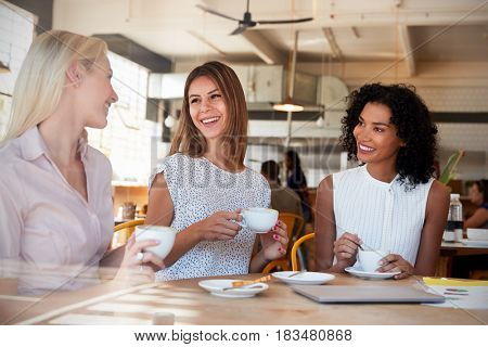 Three Businesswomen Meet In Coffee Shop Shot Through Window