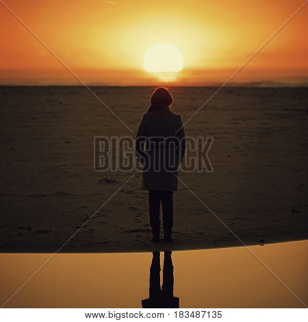 Woman watches the sunset on the beach