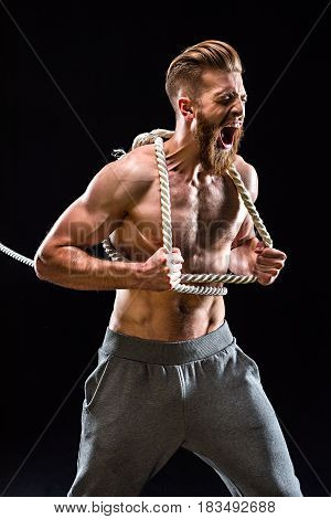 Handsome Bearded Sportsman Yelling And Pulling Rope Isolated On Black