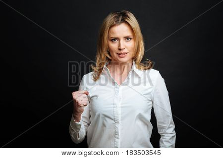 Going to prove the truth. Determined charismatic involved woman expressing determination while showing the fist and standing isolated in white background