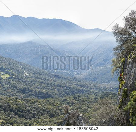 Landscape of mountains in mist and alpinist climbing rock
