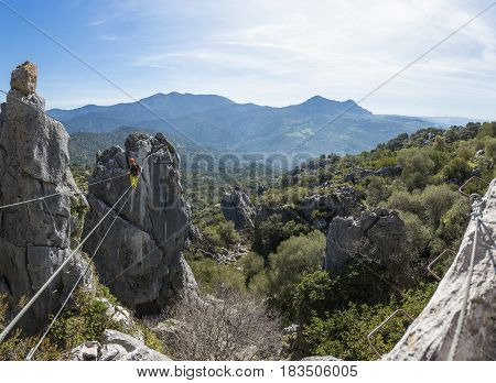 Male climber wearing special clothing and walking on rope with landscape on background