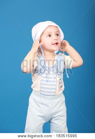 Baby in marine costume. Surprised looks aside. On a blue background