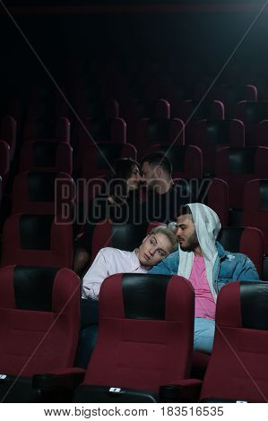 Two romantic couples in movie theater. Couple in love foreground sitting and hugging while another two kissing. Cinema, entertainment and leisure concept.