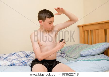 Young caucasian teenage boy using antiperspirant in the morning