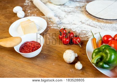 Different Pizza Ingredients, Vegetables And Dough On Wooden Tabletop