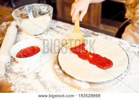 Partial View Of Girl Putting Tomato Sauce On Pizza Dough