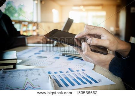 Team job succes. Closeup photo young hands business managers holding tablet working with new startup project in office.Analyze document plan Contemporary notebook on wood table.
