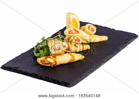 Rolls of thin pancakes with smoked salmon, cream cheese with rocket on stone on white