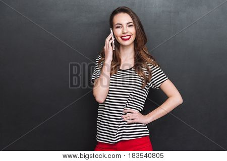Cheeerful woman talking on phone isolated over grey background