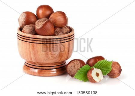 Hazelnuts with leaves in a wooden bowl isolated on white background.