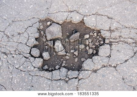 large pit with stones on the asphalt highway.
